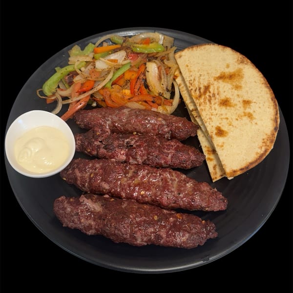 Sharjah Mediterranean Grill's kofta kebab plate with pita bread, grilled vegetables, and a side of sauce.