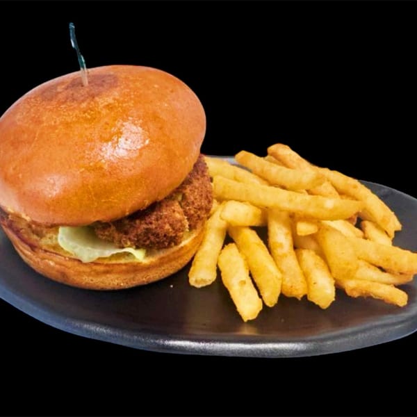 Crispy chicken burger with lettuce and sauce, served with golden french fries on a black plate.