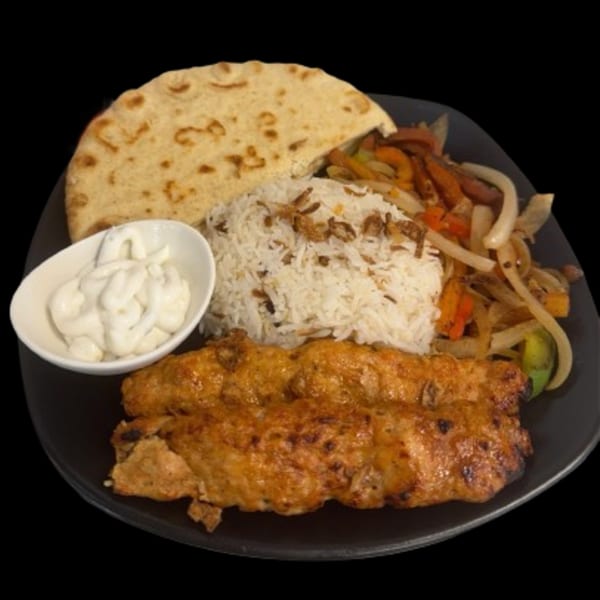 Sharjah Mediterranean Grill's chicken kebab plate with rice, pita bread, sautéed vegetables, and white sauce.